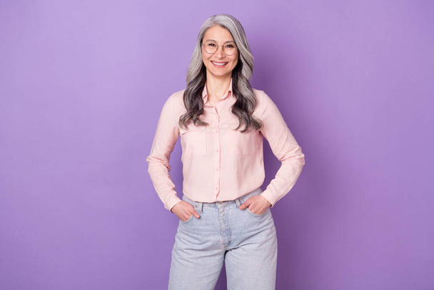 Portrait of attractive cheerful businesswoman specialist holding hands in pockets isolated over violet purple color background - Fotoğraf, Görsel