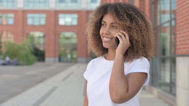Jeune femme africaine parlant au téléphone, en plein air - Photo, image