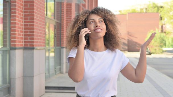 Nuori afrikkalainen nainen puhuu puhelimessa kävellessään ulkona - Valokuva, kuva
