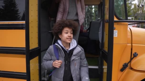 Wieloetniczni uczniowie schodzący po schodach autobusu szkolnego - Materiał filmowy, wideo