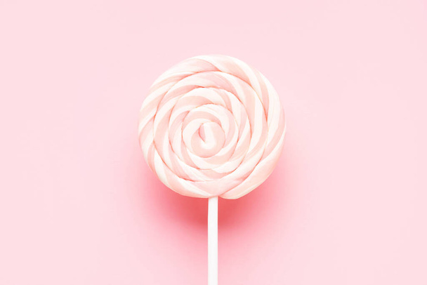 Pink lollipop on a white stick on a pink background. Top view, copy space for text - Fotografie, Obrázek