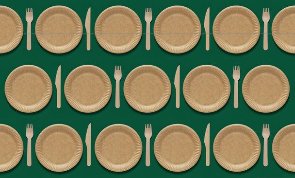 Eco-friendly disposable tableware for food. Repeating pattern with forks, knives and plates over green background. Top view - Foto, Bild