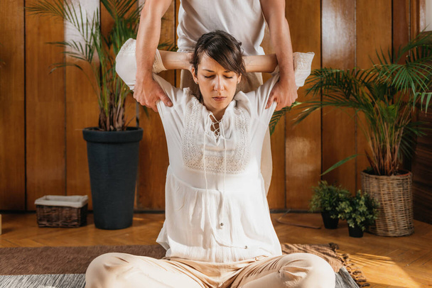 Thaise Full Body Massage - Armen strekken. Thaise massage mannelijke beoefenaar masseren jonge vrouw door passieve stretching technieken in een luxe spa en wellness centrum. - Foto, afbeelding