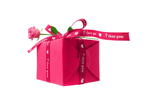 Coffret cadeau enveloppé dans un papier rouge avec fleur de rose isolée sur un blanc - Photo, image