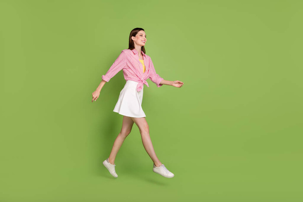 Full size profile side photo of smiling curious lady jumping relaxing on spring weekend isolated on green color background - 写真・画像