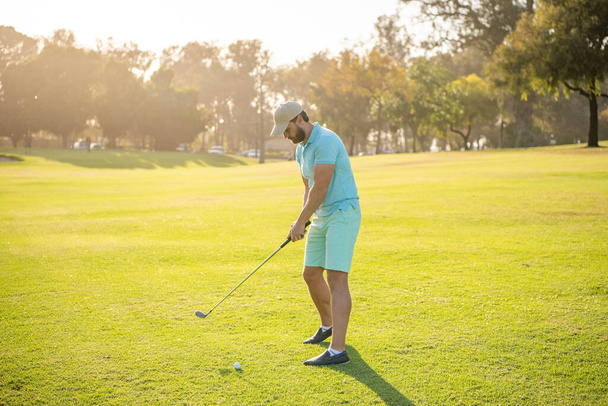 Άντρας παίκτης του γκολφ σε επαγγελματικό γήπεδο γκολφ. πορτρέτο του παίκτη του γκολφ στο καπέλο με μπαστούνι του γκολφ. - Φωτογραφία, εικόνα