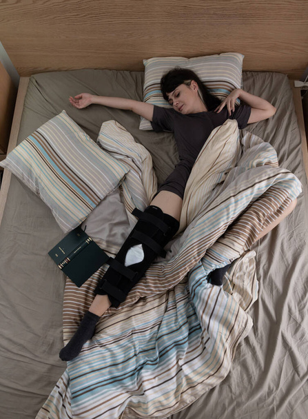 Frau mit ACL-Operation schläft zu Hause im Bett. - Foto, Bild