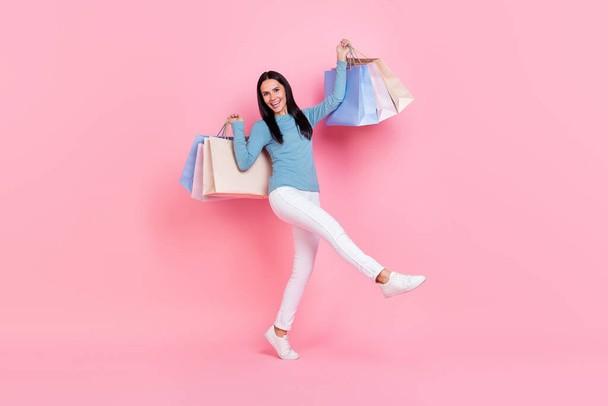 Photo of adorable sweet lady dressed blue shirt smiling walking rising bargains isolated pink color background - Fotografie, Obrázek