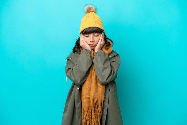 若いですラテン女性身に着けている冬のジャケット隔離された青の背景 - 写真・画像