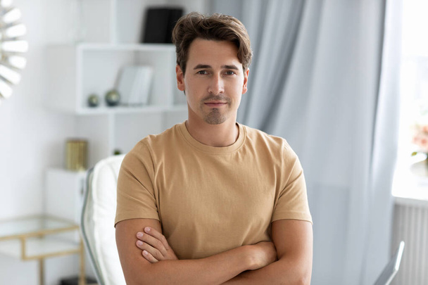 Portrait of a young positive man with crossed arms indoors. - Foto, Imagen