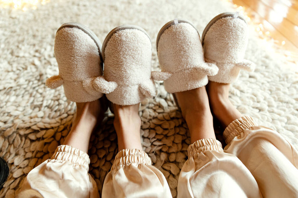 beautiful slippers on the feet of girls in the form of a lamb. slippers on sexy female legs. two pairs of slippers. view from above. - Photo, image
