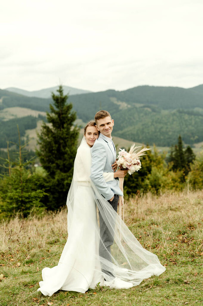 young wedding couple gently hugging after the wedding ceremony in the mountains. beautiful wedding day - Φωτογραφία, εικόνα