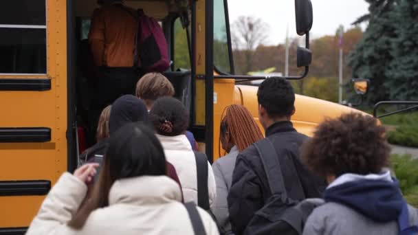 Ομάδα πολυφυλετικών μαθητών που εισέρχονται στο σχολικό λεωφορείο - Πλάνα, βίντεο