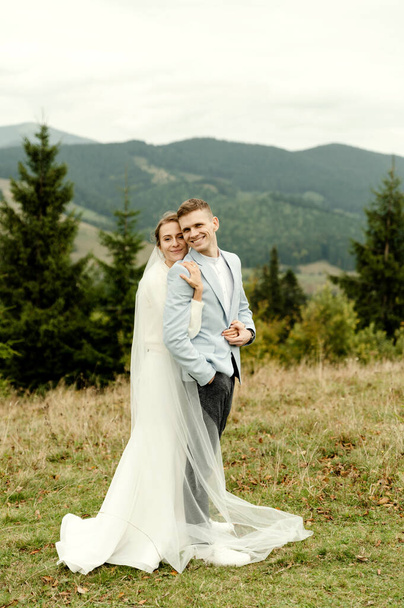 young wedding couple gently hugging after the wedding ceremony in the mountains. beautiful wedding day - Φωτογραφία, εικόνα