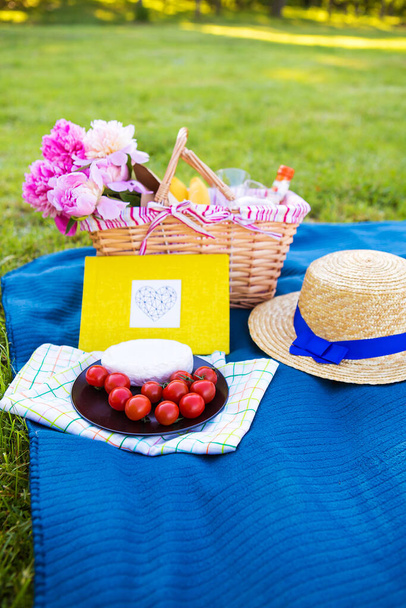 Mooie bloemen in een mand en geel album liggen op de gras-heldere picknick - Foto, afbeelding