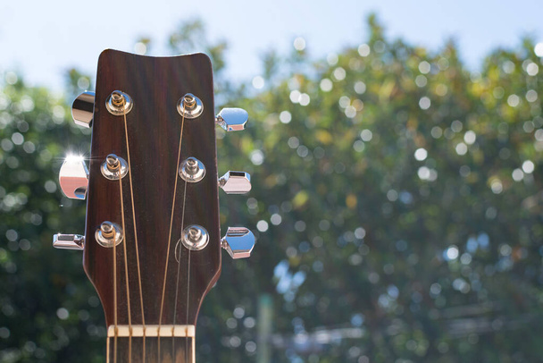 Selectieve focus van een outdoor akoestische gitaar headstock en fret. - Foto, afbeelding