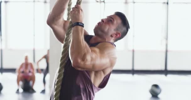 Arrampicata verso i suoi obiettivi di fitness. 4k video di un giovane muscoloso che si arrampica su una corda in palestra. - Filmati, video