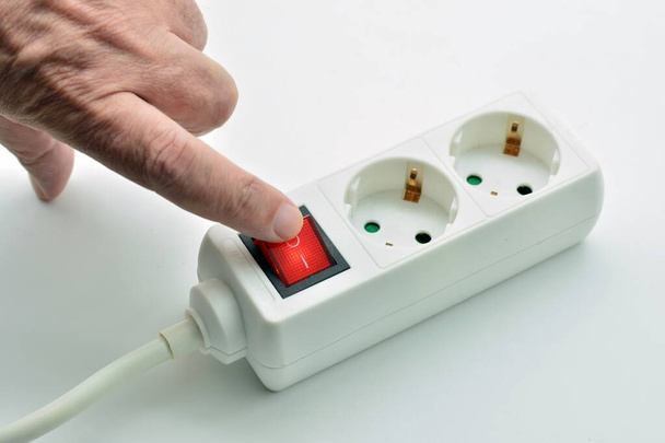 Doigt éteignant le bouton du connecteur d'alimentation pour économiser l'électricité - Photo, image
