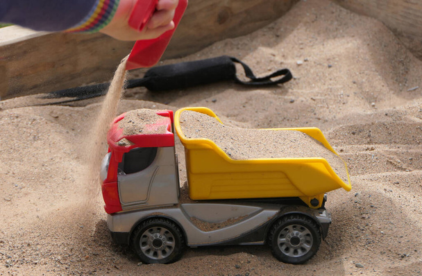 Kum çukurunda oyuncaklarla oynayan bir çocuk - Fotoğraf, Görsel