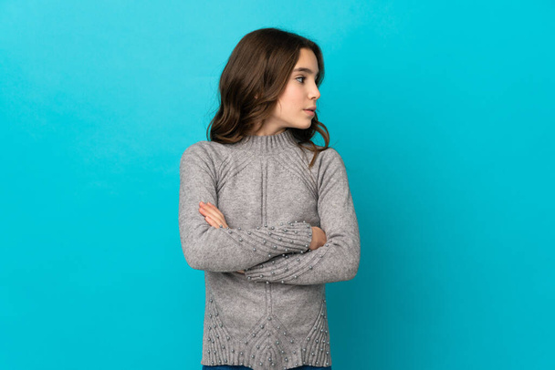 Little caucasian girl isolated on blue background keeping the arms crossed - Foto, Imagen