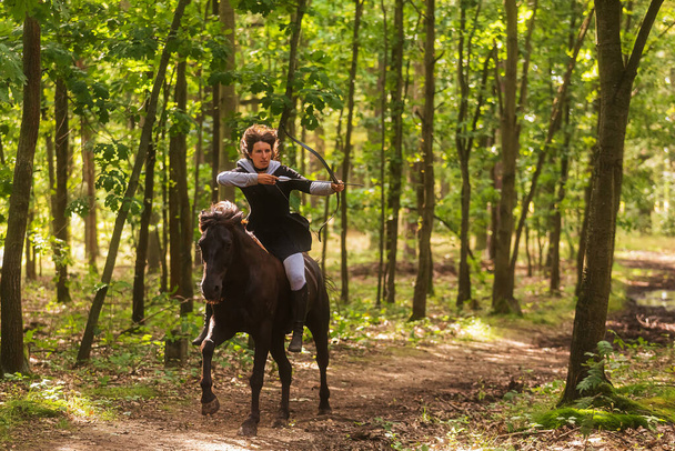 жінка на коні стріляє бантом в лісі
 - Фото, зображення