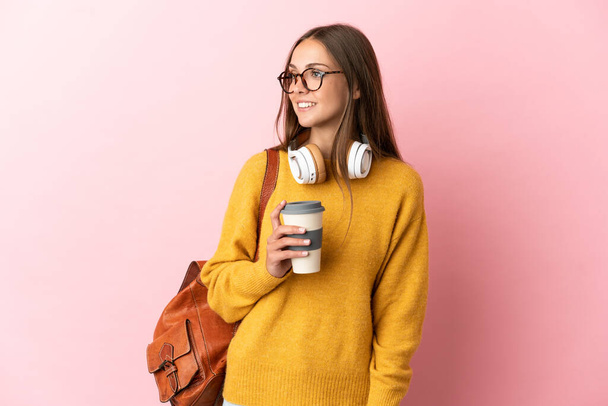 Jeune étudiante femme sur fond rose isolé regardant vers le côté et souriant - Photo, image