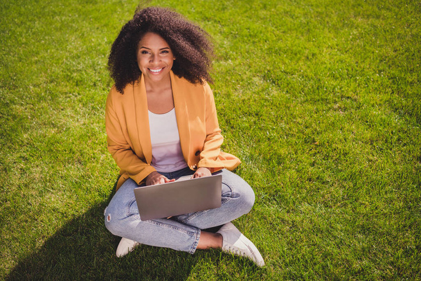 Above high angle view portrait of attractive cheerful girl sitting on grass using laptop learning remotely outdoors - Foto, immagini