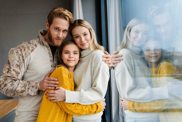 Beautiful happy young family hugging and smiling indoors - Photo, image
