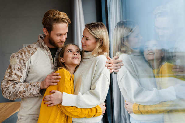 Beautiful happy young family hugging and smiling indoors - Fotoğraf, Görsel
