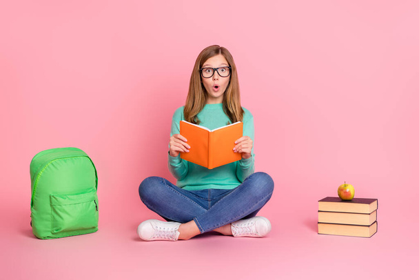 Photo of impressed girl wear turquoise sweater reading book school supplies isolated pink color background - Foto, afbeelding