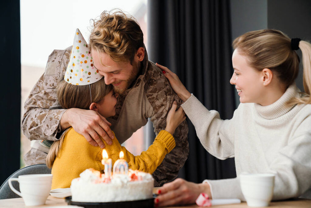 Beautiful happy family hugging while celebrating birthday of daughter at home - Foto, Imagen