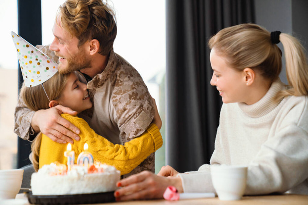 Beautiful happy family hugging while celebrating birthday of daughter at home - Photo, image