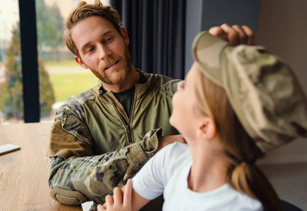 Masculine happy military man making fun with her daughter at home - Foto, Imagem