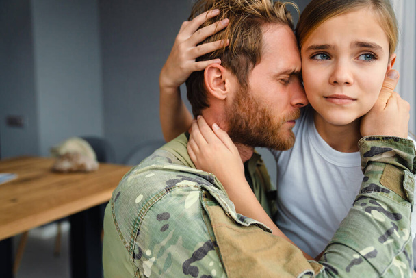 Masculine sad military man hugging her upset daughter indoors - Zdjęcie, obraz