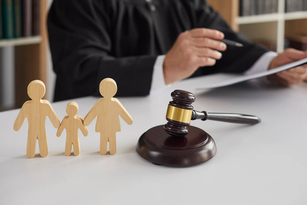 Wooden figurines of family with child and gavel on background of judge conducting divorce process. - Φωτογραφία, εικόνα