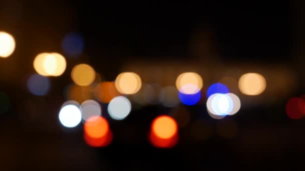 Όμορφη λαμπερή bokeh σε σκούρο θολή φόντο τη νύχτα. Το στρογγυλό πολύχρωμο bokeh λάμψη από τα φώτα των αυτοκινήτων στο δρόμο της πόλης. Εκτός εστίασης με θολή εικόνα. Μη εστιασμένα φώτα της πόλης. Κυκλοφορίας bokeh. Περίληψη - Πλάνα, βίντεο
