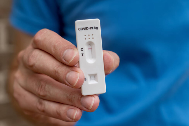 Hände halten Covid-19 Schnellantigentestkassette mit negativem Ergebnis des diagnostischen Schnelltests zu Hause - Foto, Bild