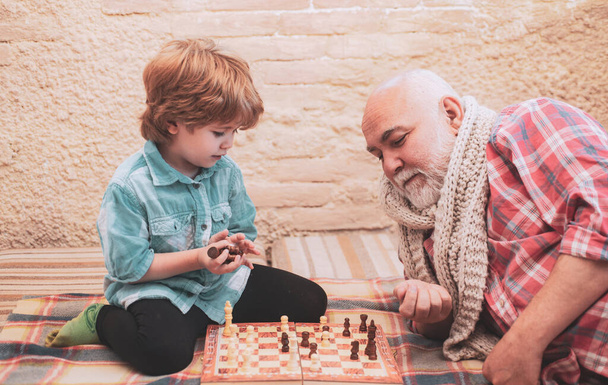 Kid Playing Chess. Little boy playing chess with his Grandfather. Chessman. Chess. Cute little boy playing chess. - Zdjęcie, obraz