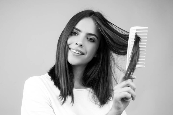 Young woman combing healthy and shiny hair, isolated on studio. - Фото, изображение