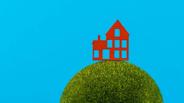 Maison symbolique en bois rouge sur une planète conditionnelle sur fond bleu - Photo, image