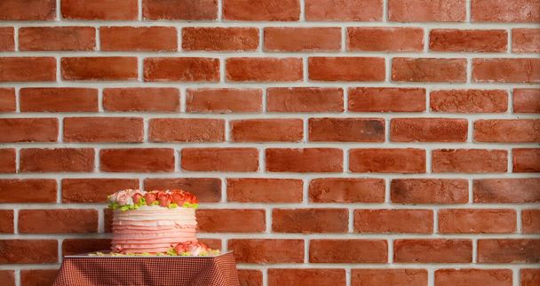 ピンクの魅力的な多層ケーキ美しいバラはレストランの茶色のレンガの壁の横にあるヴィンテージバレンタインパーティーで愛のお祝いのために提供されるデザートのテーブルの上に置くように装飾されたトッピングクリームとして. - 写真・画像