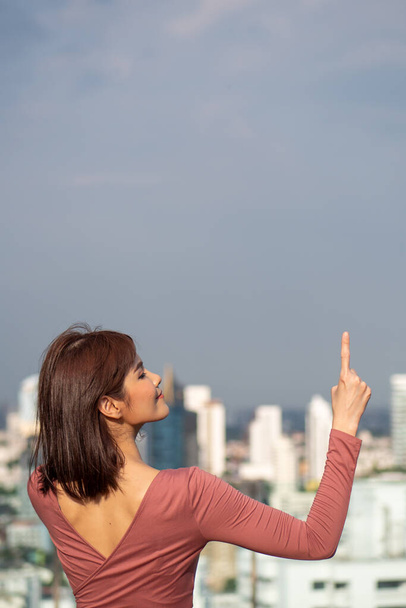 asian woman pointing up in urban environment - Foto, Bild
