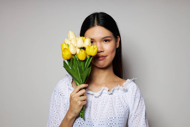 woman with Asian appearance in a white shirt flowers spring posing light background unaltered - Fotografie, Obrázek