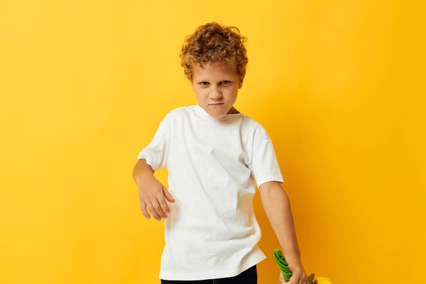 Zdjęcie portret kręcone mały chłopiec z żółtymi kwiatami pozowanie dzieciństwo zabawy kolor tło bez zmian - Zdjęcie, obraz