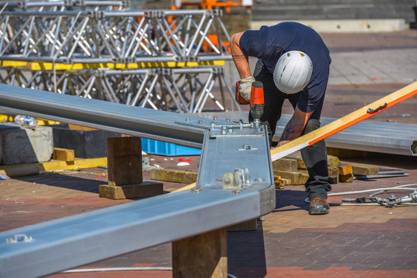 A construction worker drilling halls in metal piece - Foto, imagen