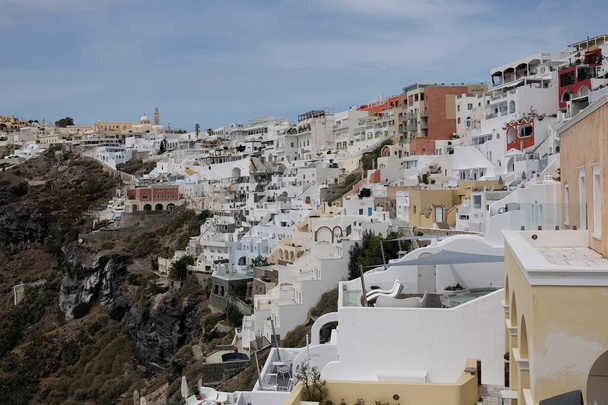 Santorini, Greece - May 7, 2021: Panoramic view of the picturesque villas with balconies of the village of Fira in Santorini Greece  - Foto, Imagen
