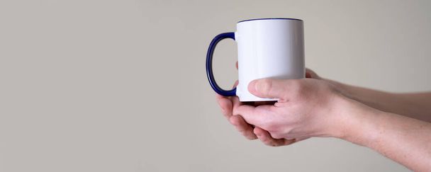 White mug in the hands of a man on a light background. The concept of delicious and hot coffee or tea. - Fotó, kép