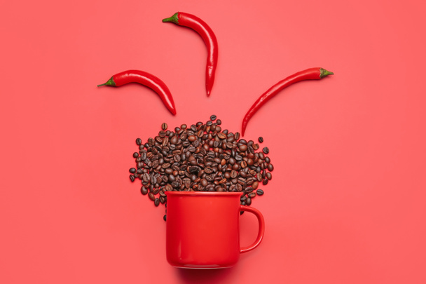 Mug with hot chili peppers and coffee beans on red background - Photo, Image