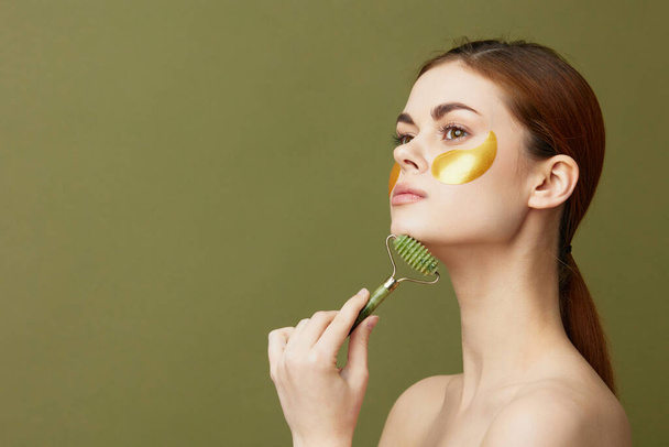pretty woman face massager golden patches on the face isolated background - Photo, Image