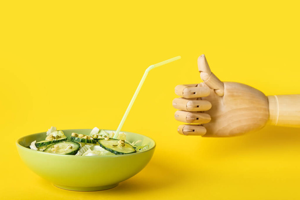Wooden hand showing thumb-up and bowl of healthy salad on yellow background - Zdjęcie, obraz